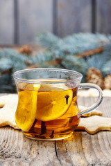 Glass of hot steaming tea among christmas decorations on wood