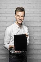 Handsome man standing on Grey wall background,Whith Tablet Pc