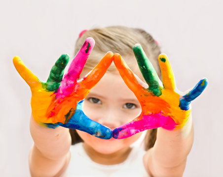 Cute little girl with hands in paint