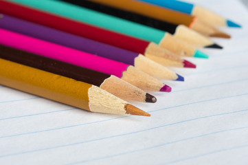 The color pencils lying on an open writing-book