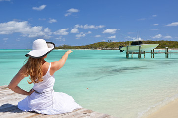 Fototapeta na wymiar Girl on the wooden jetty looking to the ocean. Exuma, Bahamas