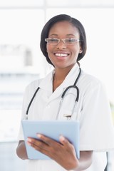 Smiling doctor using digital tablet