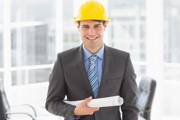 Happy architect holding blueprints smiling at camera