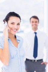 Obraz premium Woman on call with male colleague in background
