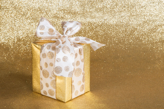 Golden gift wrapped present on gold background
