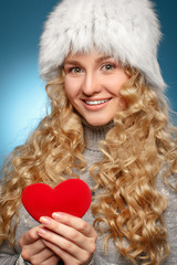 Girl in winter clothes giving heart. Concept of Valentine's Day