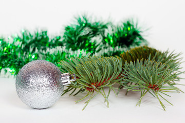 Fototapeta na wymiar Silvery ball, pine branch and green Christmas tinsel