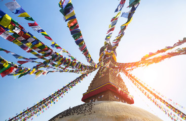 Prayer flags flying against the sun from the Boudhanath Stupa.