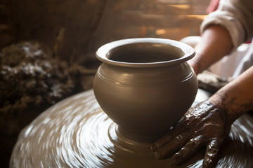 Close-up of hands working clay on potter's wheel.
