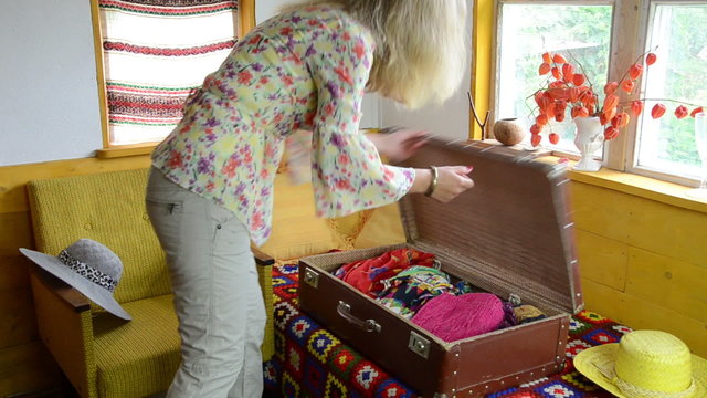Pretty woman carry big retro trunk and take out clothes from it