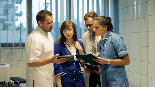 Young group of doctors discussing over tablet computer