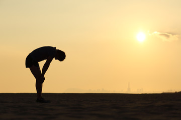 Silhouette of an exhausted sportsman at sunset © Antonioguillem