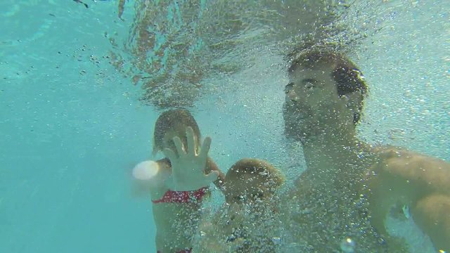 Dad with kids jumping in swimming pool