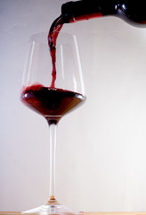 Red wine pouring into a glass with white background