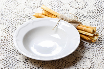 Empty bowl and traditional italian breadsticks on beautiful lace