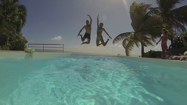 Couple jumping in infinity pool water