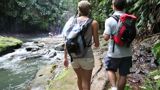 Back view of trekkers reaching waterfall