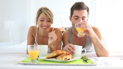 Cheerful young couple having breakfast in bed - Powered by Adobe