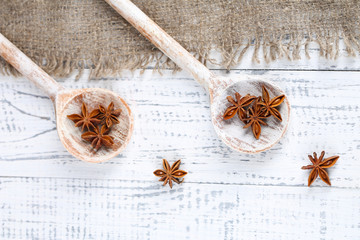 Star anise in wooden spoon, on wooden background