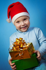 Boy in a cap of Santa Claus with gifts