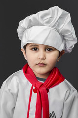 Little boy preparing healthy food on kitchen over grey backgroun