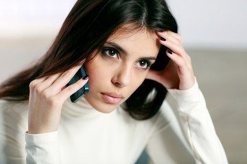 Young pensive woman talking on the phone