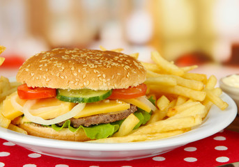 Tasty cheeseburger with fried potatoes, on bright background