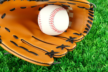 Baseball glove and ball on grass background