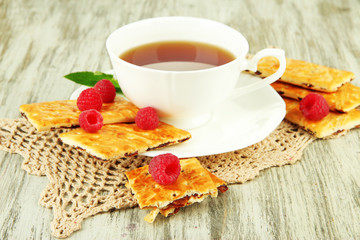 Cup of tea with cookies and raspberries on table close-up
