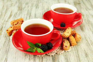 Cups of tea with cookies and blackberry on table close-up