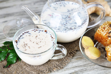 Teapot and cup of tea with milk and spices