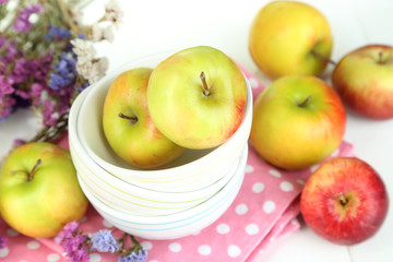 Juicy apples on plate on white wooden table