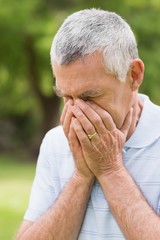 Senior man with head in hands at park