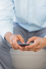 Man sending a text sitting on sofa