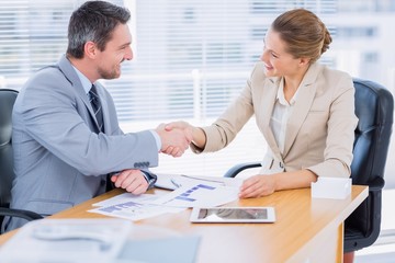 Colleagues shaking hands in a business meeting at office desk