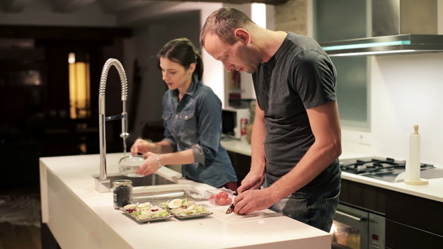 Young couple preparing, eating food in the kitchen