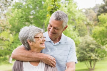 Obraz premium Senior man embracing woman from behind at park