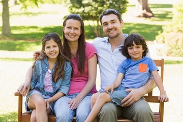 Fototapeta premium Couple with young kids sitting on park bench
