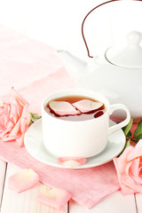 teapot and cup of tea with roses and on white wooden table