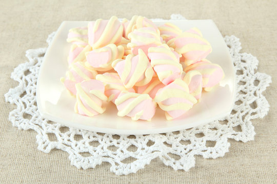 Marshmallows on plate on light background