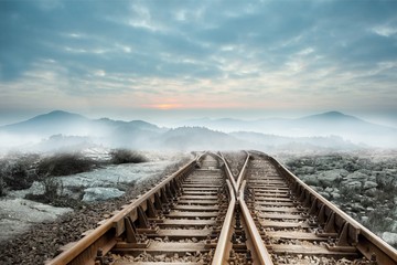 Railway tracks leading to misty mountains