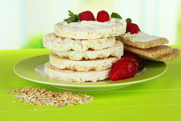 Tasty crispbread with berries on plate, on green table
