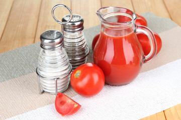 Tomato juice in glass jug, on wooden background