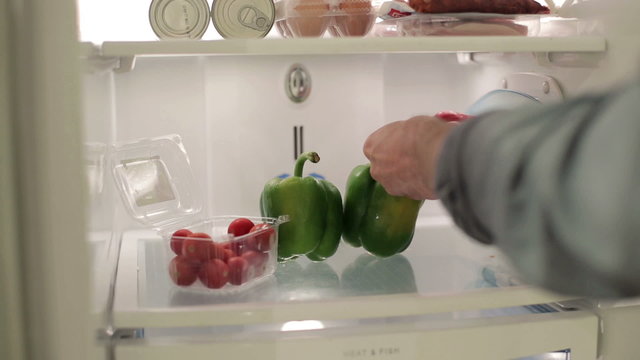 Male hand taking peppers, vegetables from the fridge