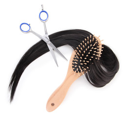 Long black hair with hairbrush and scissors isolated on white