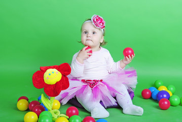 Fototapeta na wymiar Small girl in rose suit on green background