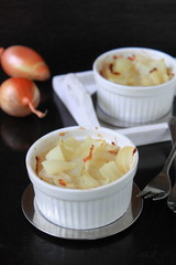 onion baked with cheese in a white plate on a black background