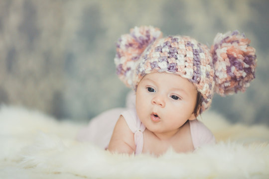 Cute newborn baby girl in knitted cap with bubonic