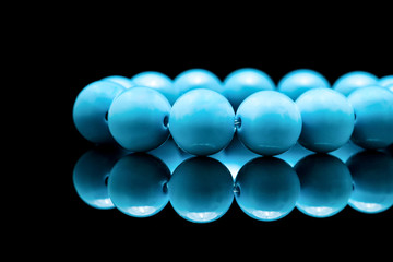 Close-up of blue coral beads on balck background.