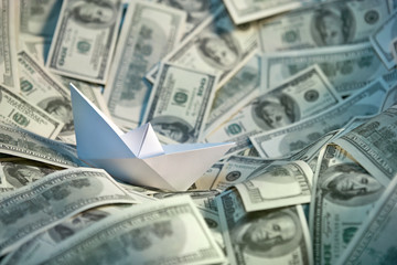 Paper ship floating on the sea of money